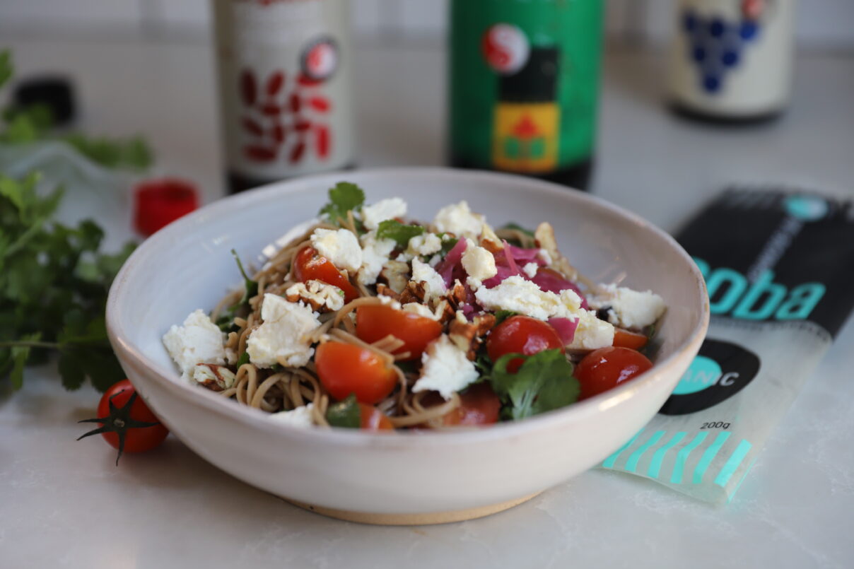 Bowl of Organic Soba Salad with tomatoes, coriander, feta and walnuts, with an Organic Miso and Shoyu dressing.