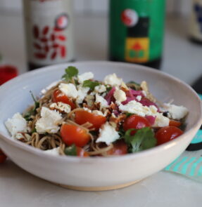 Bowl of Organic Soba Salad with tomatoes, coriander, feta and walnuts, with an Organic Miso and Shoyu dressing.